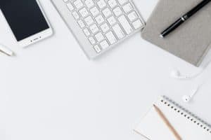 Keyboard, phone and notebooks on white table