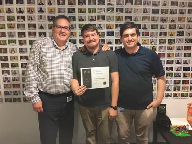 Three people posing with certificate